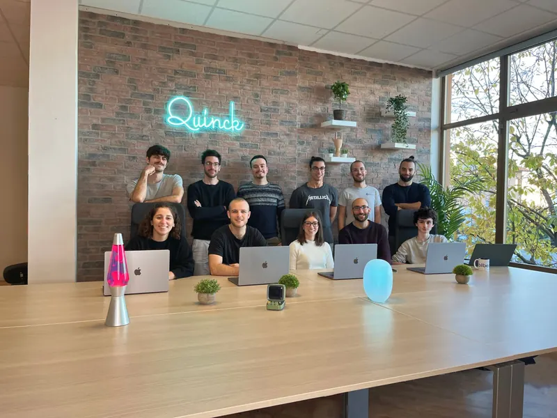 Il team Quinck nella nuova sala riunioni con l'insegna al neon, 2022