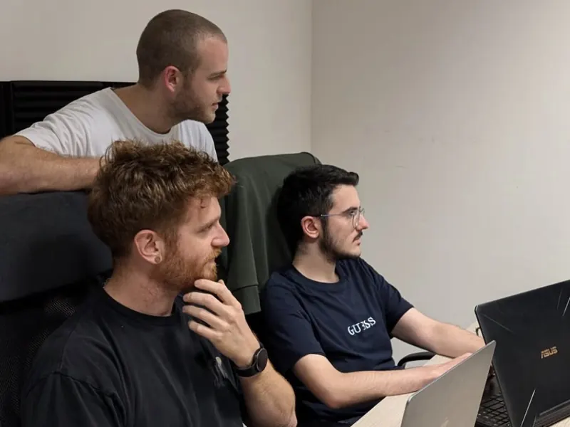 Tre sviluppatori Quinck al lavoro davanti ai laptop in ufficio nel 2024