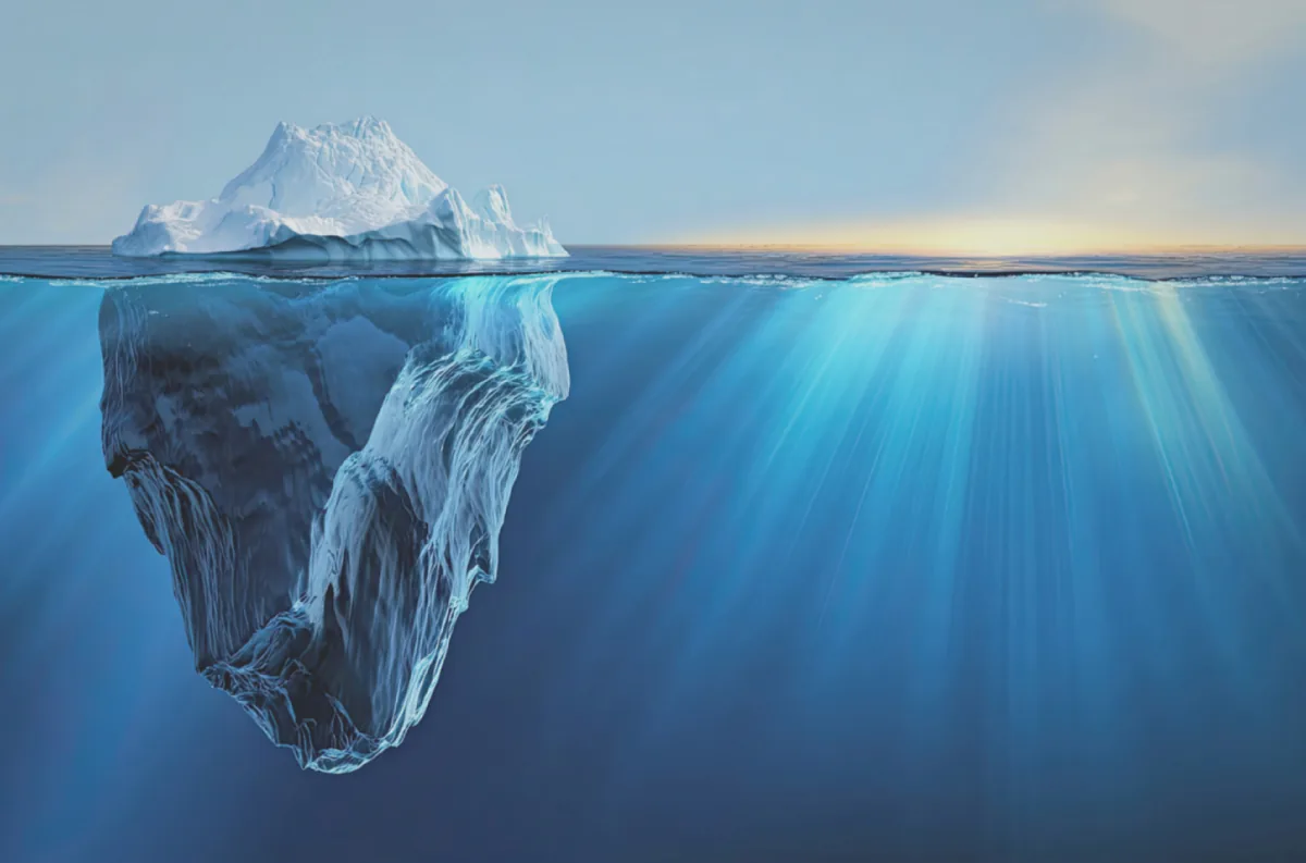 Iceberg sommerso visto da sotto la superficie: la parte visibile è piccola, la massa nascosta è enorme, metafora del debito tecnico nel codice generato con l'AI